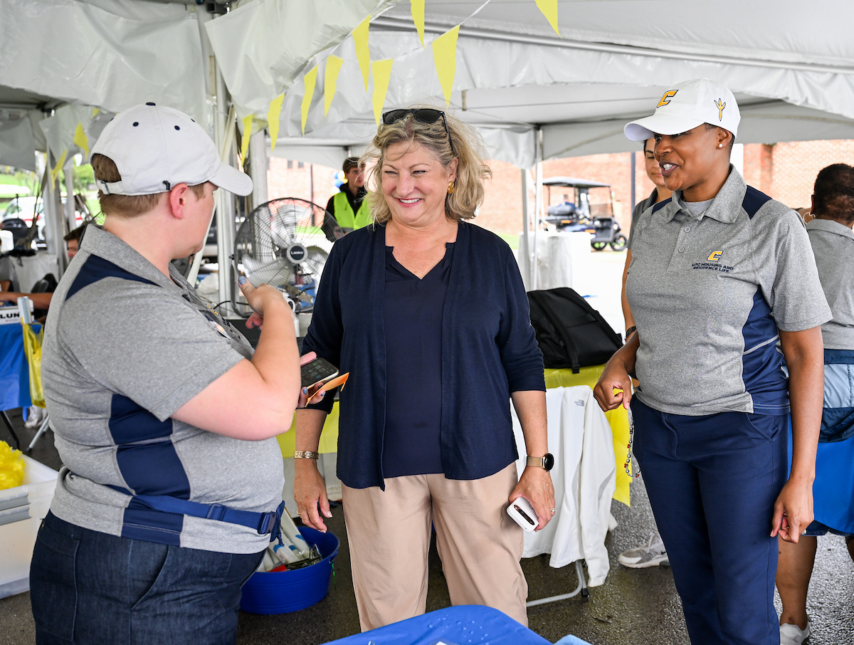 Chancellor Lori Bruce and Artanya Wesley stand under a tent outside of West Campus Housing.