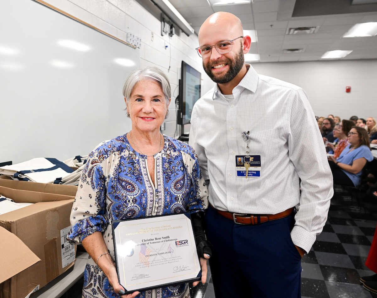 Dr. Chris Smith holding her award certificate. She is standing next to Terry Ellis.