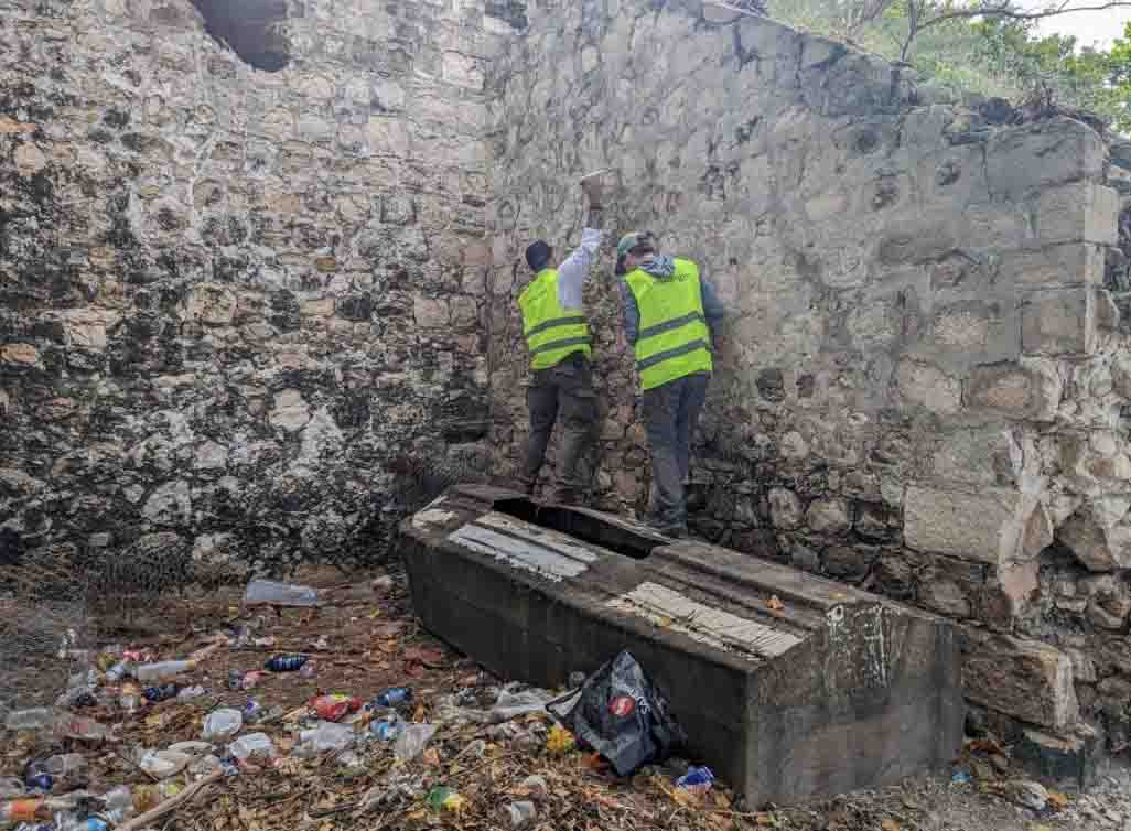 Van Slyke and Smith, wearing yellow vests, stand near an old brick wall.