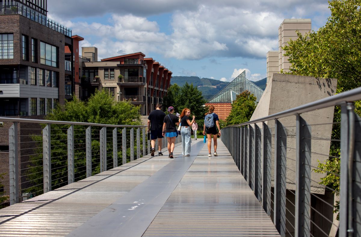 4 UTC students walk across the Holmberg Glass Bridge