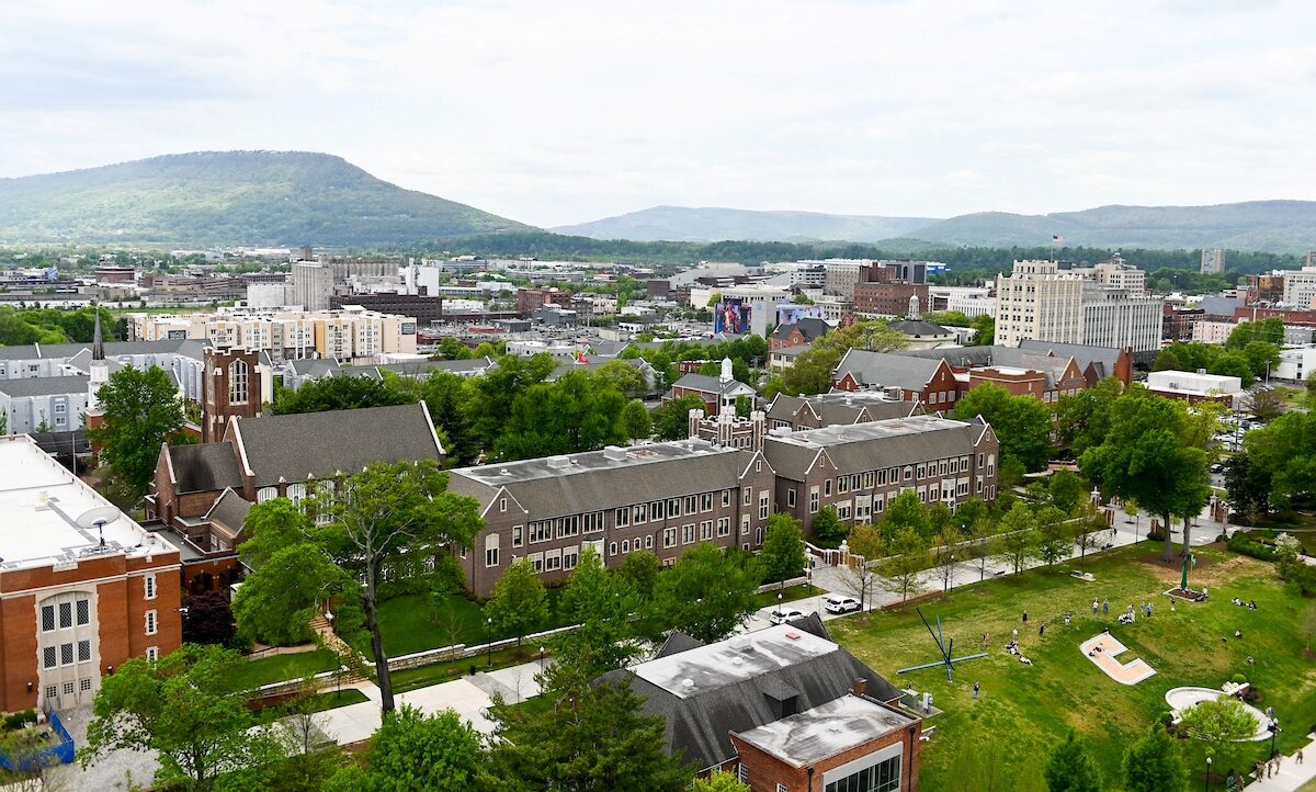 An aerial view of UTC and Chattanooga. Hooper and Race Halls are in the foreground along with the edge of Chamberlain Field, including the Power C. Downtown and mountains are in the background.