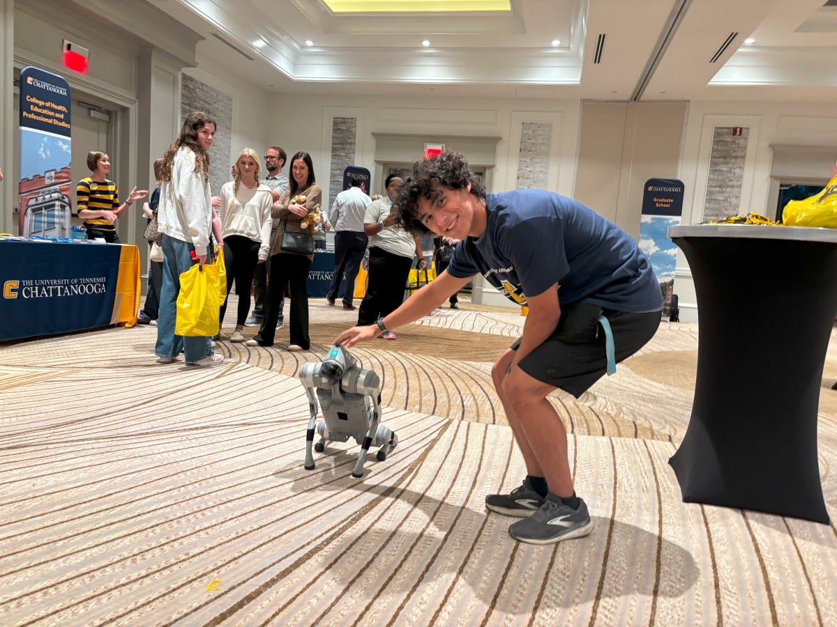 A prospective UTC student meets one of the mechatronics robot dogs