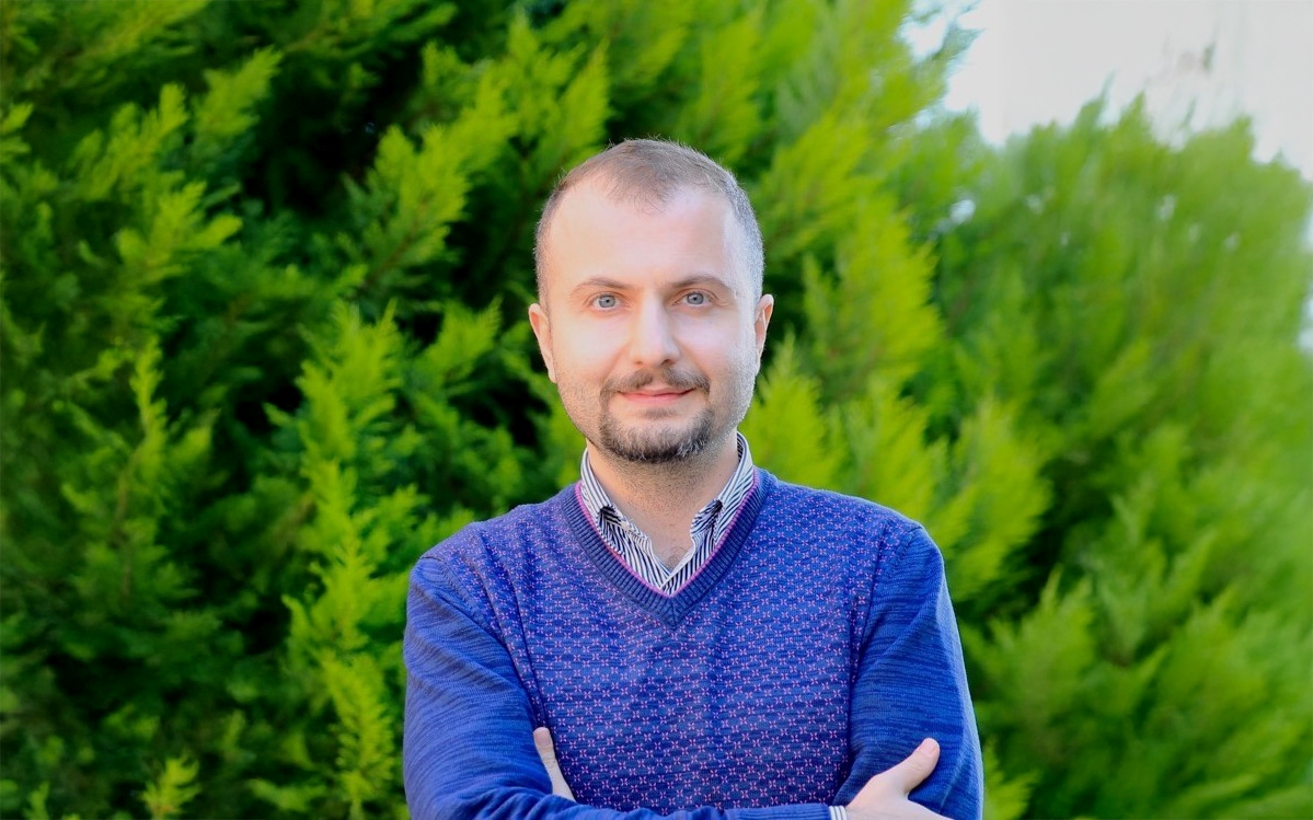 Dr. Murat Barisik stands in front of a tree