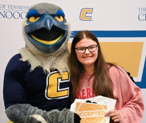 A student stands next to Scrappy for a photo after being accepted into UTC at a Power C Tour event.