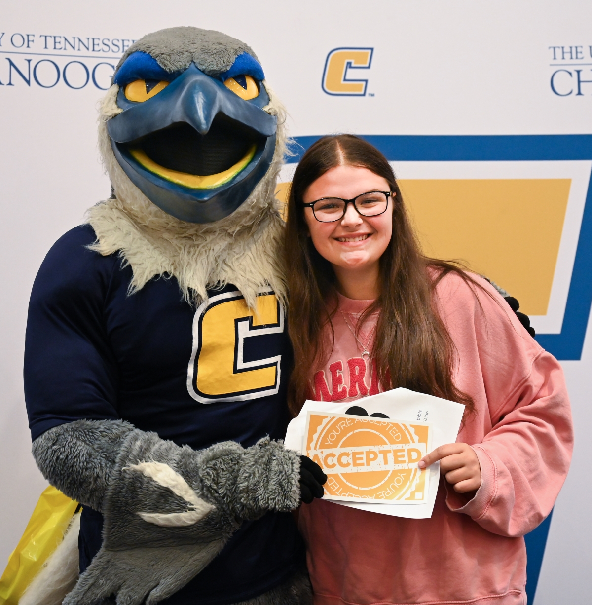 A student stands next to Scrappy for a photo after being accepted into UTC at a Power C Tour event.