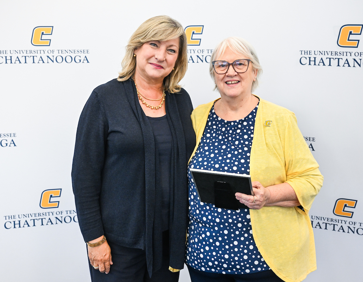Chancellor Lori Bruce standing next to Sandra Jones, who is holding a plaque, in front of a UTC-branded backdrop at the 2025 UTC Service Awards.