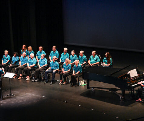 Members of the Trembling Troubadours sitting in chairs on the Roland Hayes Concert Hall stage
