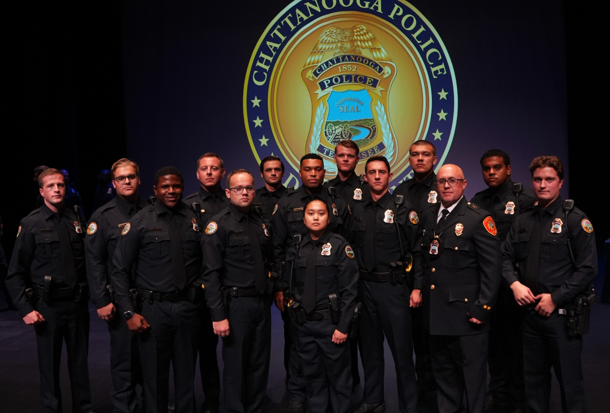 Chattanooga Police Department academy graduates stand in front of a CPD logo in the Roland Hayes Concert Hall
