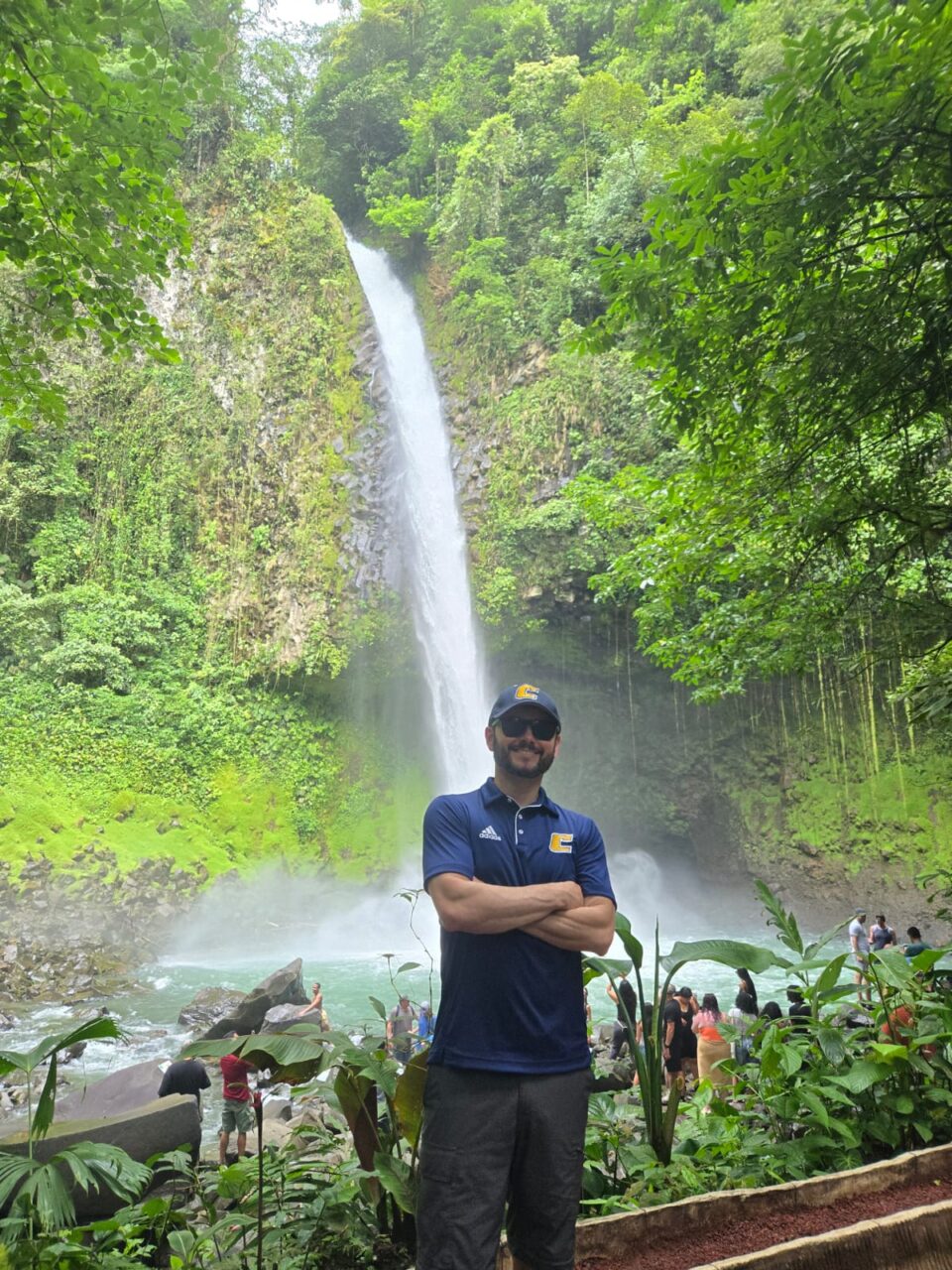 Person standing with arms folded in front of a waterfall