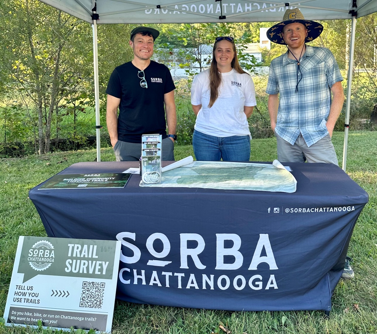 Sunshine Loveless, Chloe Wesson and Dr. Ryan Zwart stand under a SORBA Chattanooga tent with a Trail Survey sign in the foreground