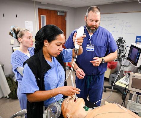 Two student nurses and a faculty member during an airways workshop working on a manikin