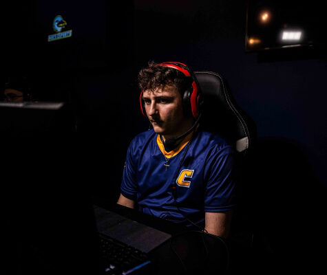 Chase Daffron wearing headphones and sitting at a video game console in the UTC Esports Complex