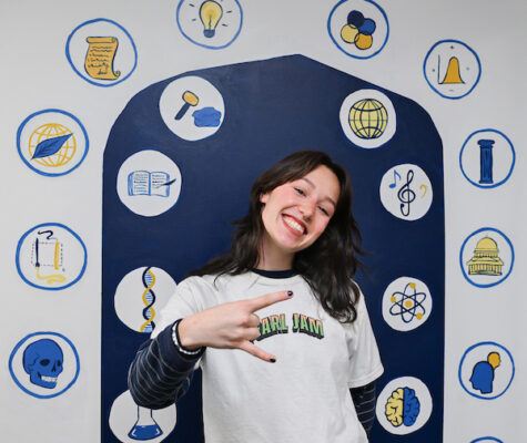 Sydney Zwart stands in front of a selfie station mural that she painted