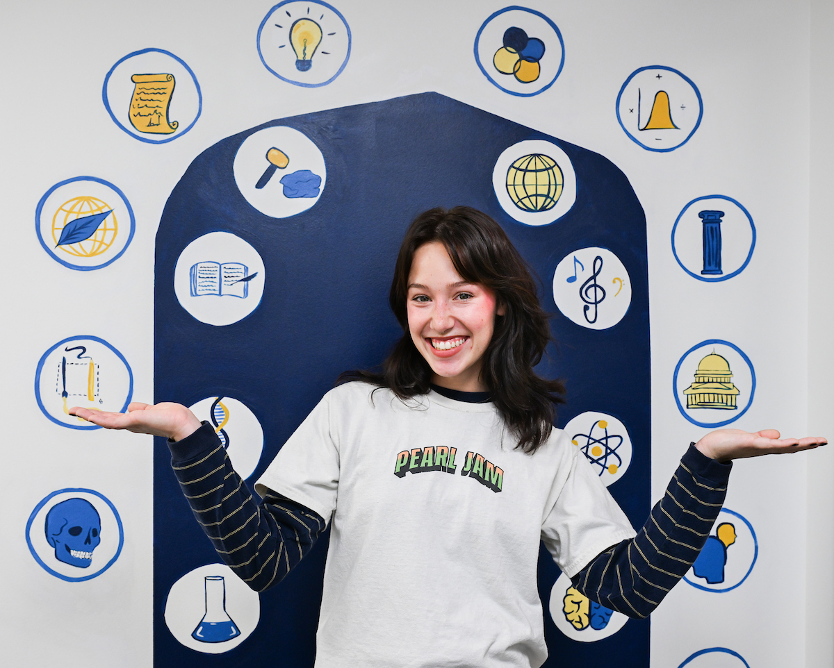 Sydney Zwart stands in front of a selfie station mural that she painted
